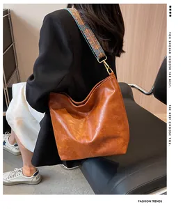 Detail of soft brown textured shoulder bag with a vibrant ethnic style wide strap