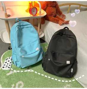 Close-up of minimalist canvas backpacks in light blue and black with cute logo patch detail