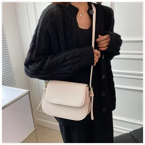 Close-up of minimalist cream white crossbody saddle bag with refined stitching details