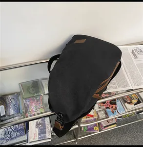 Dettaglio della borsa a tracolla in tela nera con inserti in pelle marrone e gancio in metallo