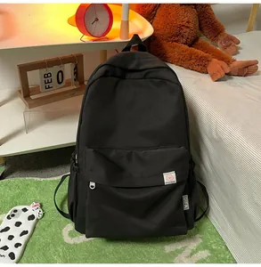 Black canvas backpack with cute pink bear embroidery and side pocket in a cozy bedroom setting