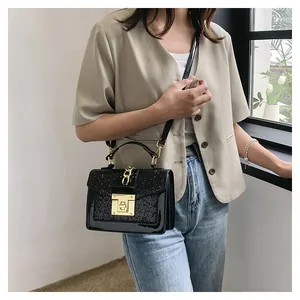 Detail view of black sequin crossbody bag with gold lock and chain shown on model