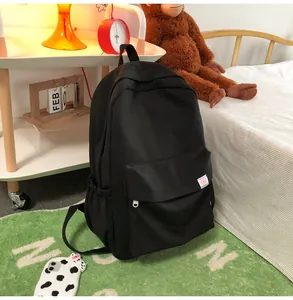 Detail of minimalist black backpack with cute pink bear patch on the front pocket