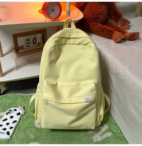 Detail of light yellow canvas backpack featuring cute bear tag and spacious front pocket
