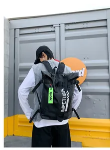 Detail van zwarte roll-top rugzak met witte tekst en neon-groen label bij een container