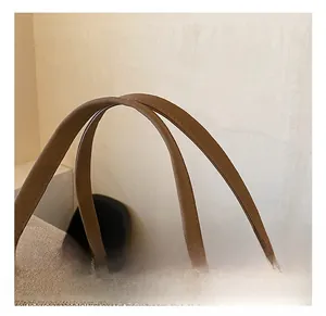 Detailed close-up of thickened brown faux leather handles and smooth metal zipper on canvas bag