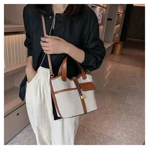 Close-up of canvas and brown leather stitching on a bucket bag with fashion tag