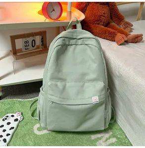 Detail of mint green corduroy backpack with brand label in a cozy bedroom setting