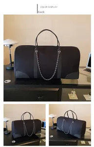 Detail view of large black canvas travel tote with decorative metal chain on office desk