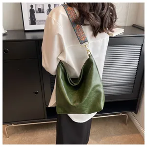 Detail of green leather tote bag with ethnic colorful embroidered wide strap and gold hardware