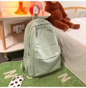Close-up of a light green fabric backpack with fine grid texture in a cozy bedroom setting