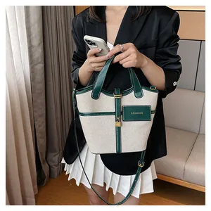 Detail of canvas bucket bag showing green leather trim, golden padlock, and fashion label