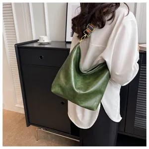 Detail of dark green leather shoulder bag with colorful patterned strap on a model