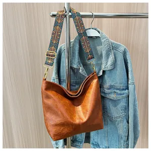 Close-up of caramel tote bag with ethnic geometric embroidered strap and gold metal hardware
