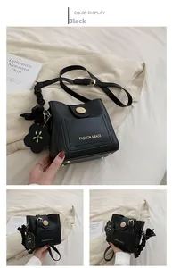 Détail du sac seau noir avec ferrures dorées et breloque florale sur fond blanc