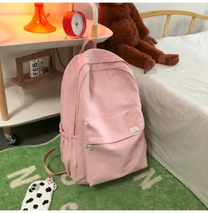 Detail of light pink canvas backpack featuring a cute bear patch in a cozy bedroom setting