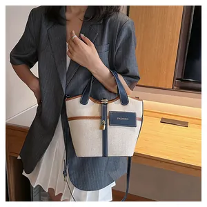Detail of vintage canvas bucket bag with blue leather trim and golden lock pendant