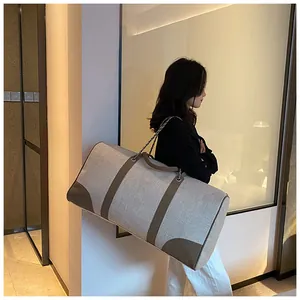 Detail of grey canvas travel tote with brown leather handles and metal chain strap