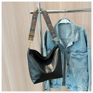 Detail of black leather tote bag with a colorful vintage geometric patterned shoulder strap