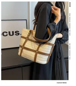 Detail of woven straw tote bag with brown leather straps and gold rivet accents