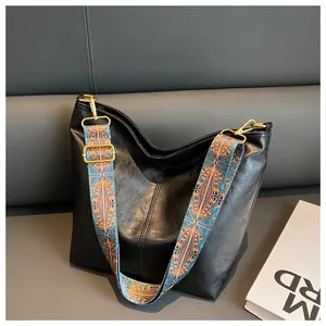 Detail of black leather hobo bag featuring a colorful ethnic style woven wide strap
