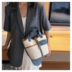 Detail of canvas bucket bag with navy blue leather trim and fashion lettering