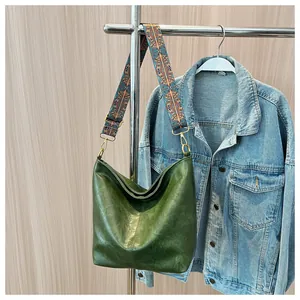 Detail of dark green hobo bag featuring a colorful patterned strap and gold metal hardware