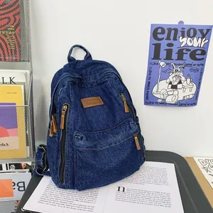 Grote denim rugzak voor dames met bruine leren patch op een bureau in studiostijl