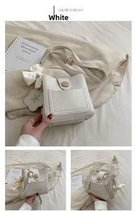 Détail du sac seau blanc avec bouton en bois, nœud en soie et pendentif floral