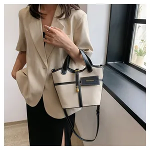 Detail view of canvas bucket bag with black leather trim and gold padlock accent