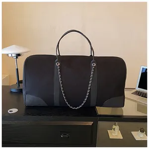 Detailed macro view of black canvas travel tote bag with leather trim and chain detail