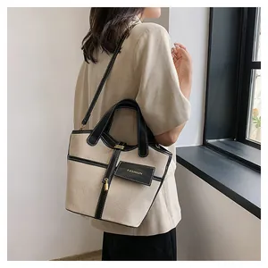 Detail of the minimalist canvas bucket bag with contrast leather trim and golden logo