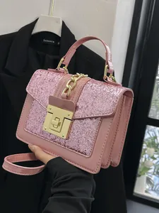 Pink glitter crossbody bag with gold hardware shown being held by a model for a chic look