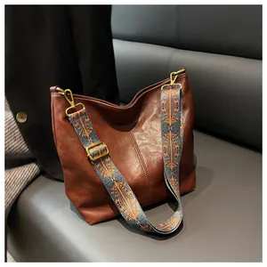 Detailed texture of brown hobo bag featuring a colorful ethnic embroidered shoulder strap