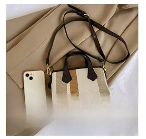 Detail presentation of small striped woven bag with leather strap and size reference