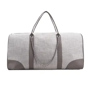Detail view of large gray canvas travel bag with brown leather accents and metal chain