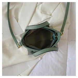 Top view of striped canvas bucket bag showing zipper interior and green leather strap