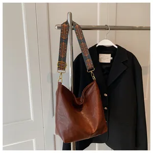 Detailed shot of brown leather tote bag featuring a vintage ethnic woven wide shoulder strap