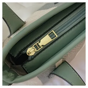 Close-up of golden metal zipper and textured canvas fabric on a sage green bucket bag