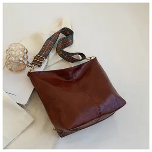 Close-up of vintage brown tote bag with textured PU leather and ethnic pattern strap