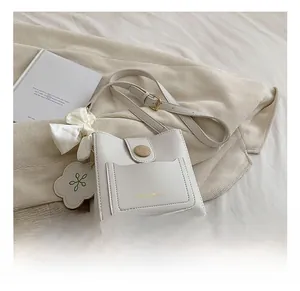 Détail du sac seau blanc crème avec nœud en soie et lettrage doré de mode