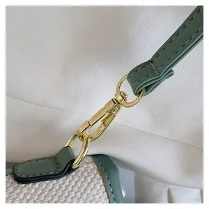 Detail of sage green leather strap and gold metal hooks on striped bucket bag