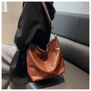 Detail of hobo bag featuring matte brown PU leather and colorful geometric woven strap