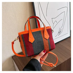 Detail of colorful striped woven mini tote bag with orange leather handles and strap
