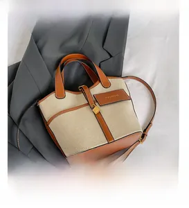Detail view of canvas bucket bag featuring leather trim, gold hardware and fashion label