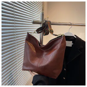Detailed shot of brown faux leather hobo bag with a decorative ethnic pattern strap