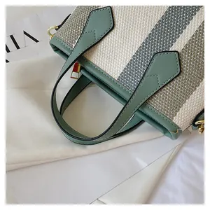 Detailed macro view of green striped canvas texture and metallic zipper of the handbag