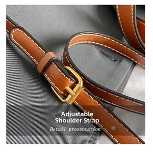 Detail of adjustable brown leather shoulder strap with gold buckle and white stitching
