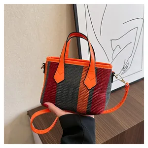 Detailed view of striped woven bag with orange PU handles and golden metal hardware