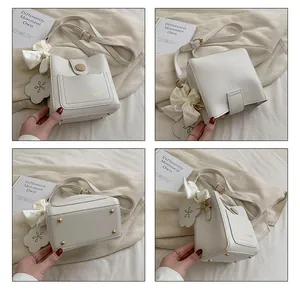 Vue détaillée du sac seau crème avec lettrage doré, clous et breloque florale décorative